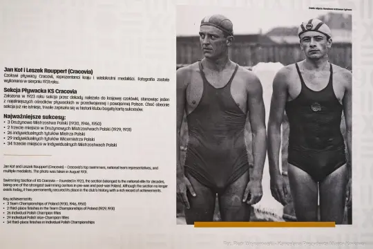 Dwaj pływacy w strojach kąpielowych, z medalami, prezentują osiągnięcia klubu KS Cracovia.