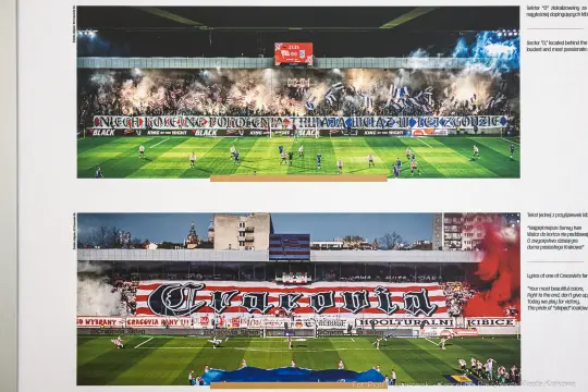 Fani na stadionie z flagami i oprawą świetlną, mecz piłkarski.