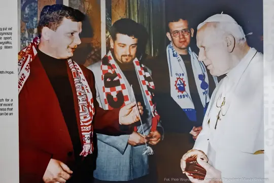 Spotkanie z papieżem, mężczyźni w szalikach sportowych, rozmowa i uśmiechy.
