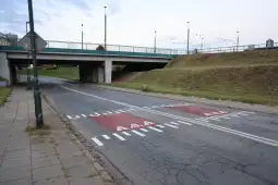 Przejazd pod wiaduktem z oznaczeniami drogowymi.