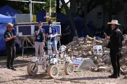 Robot marsjański w trakcie testów w terenie, obok zespołu inżynierów.