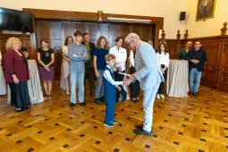 Uroczystość wręczenia nagrody młodemu chłopcu w towarzystwie grupy osób.
