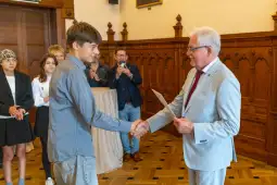 Młody mężczyzna uścisnął dłoń starszemu mężczyźnie podczas ceremonii wręczenia dyplomu.