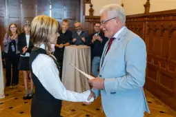 Uroczystość wręczenia dyplomu, gratulacje i uściski dłoni.