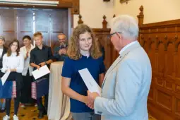 Uroczystość wręczenia nagród dla uczniów w eleganckim wnętrzu.