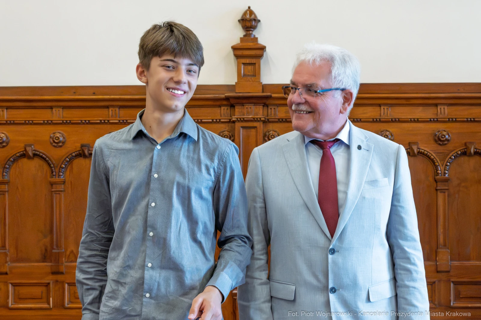 Młody mężczyzna i starszy mężczyzna uśmiechają się, stojąc obok siebie w eleganckim wnętrzu.  Autor: Piotr Wojnarowski