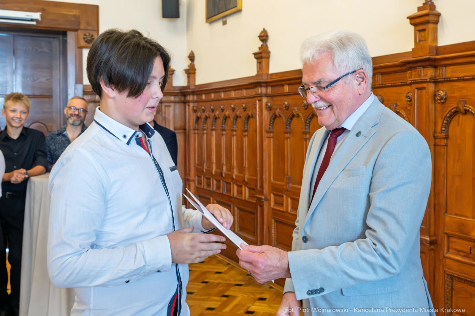 Młody chłopak odbiera dyplom od uśmiechniętego mężczyzny w eleganckim garniturze.  Autor: Piotr Wojnarowski