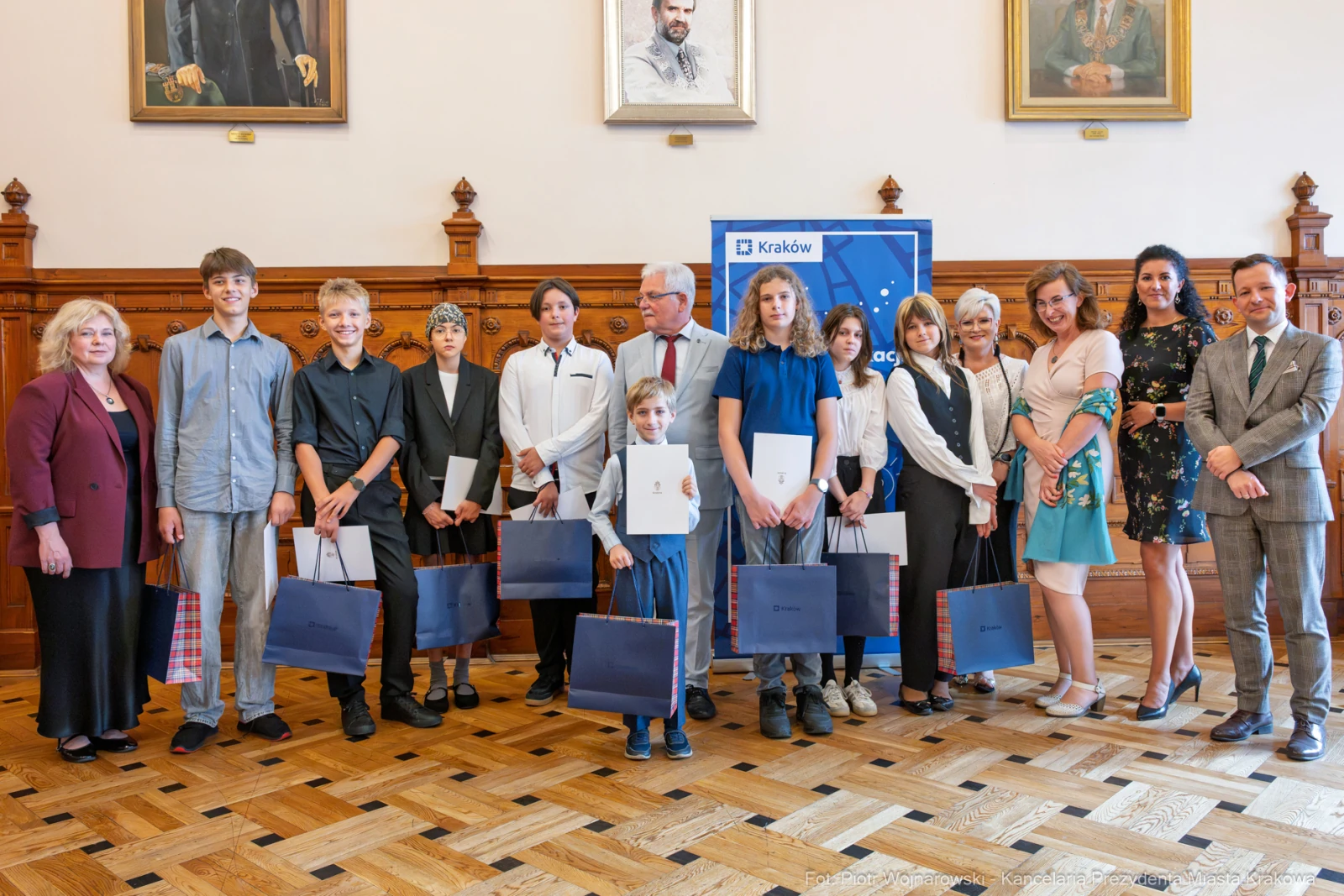 Grupa ludzi z nagrodami w sali z portretami na ścianach.  Autor: Piotr Wojnarowski