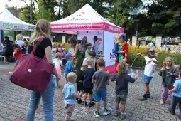 Dzieci bawią się w pobliżu stoiska z animatorem, tworząc bańki mydlane.