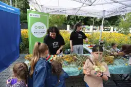 Warsztaty rękodzielnicze w plenerze, dzieci tworzą kompozycje z roślin.