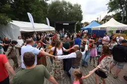 Ludzie tańczą w kręgu podczas festiwalu na świeżym powietrzu.