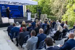 Wydarzenie na świeżym powietrzu z mówcami i publicznością w eleganckim otoczeniu.