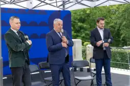 Trzech mężczyzn z mikrofonami podczas wystąpienia na scenie.