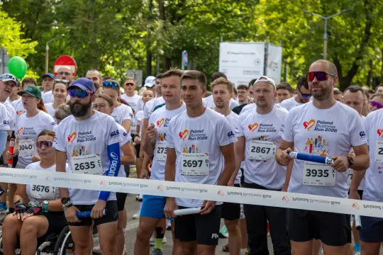 Biegacze w koszulkach startowych czekają na sygnał do rozpoczęcia biegu.