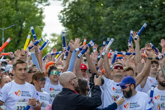 Uczestnicy biegu z radością trzymają pałeczki, przygotowując się do startu.
