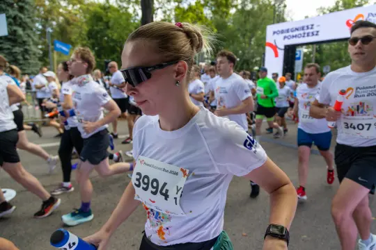 Biegacze uczestniczą w wydarzeniu sportowym, w tle widoczny start biegu.