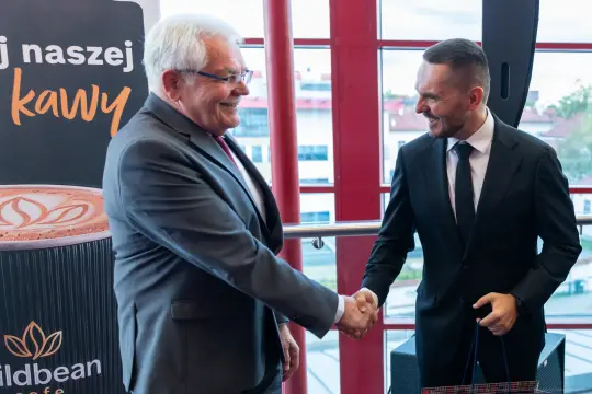 Dwaj mężczyźni uścisnęli sobie dłonie w formalnej atmosferze.