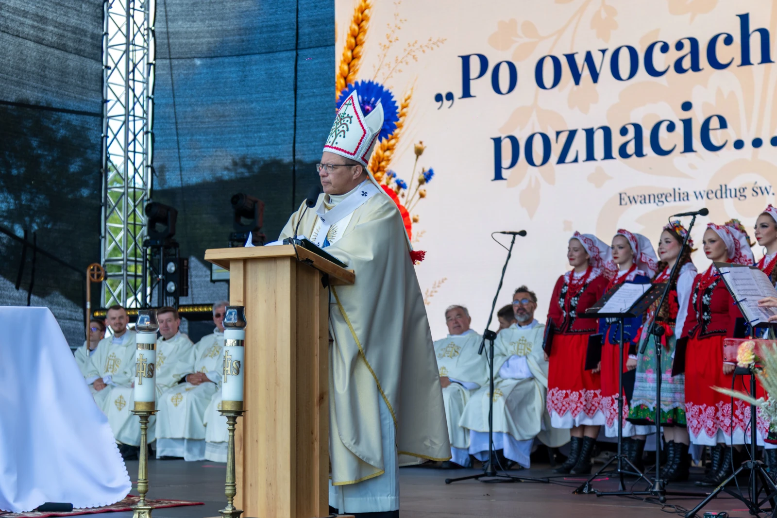 Kapłan wygłaszający kazanie podczas uroczystości religijnej, w tle chór w tradycyjnych strojach.  Autor: Bogusław Świerzowski
