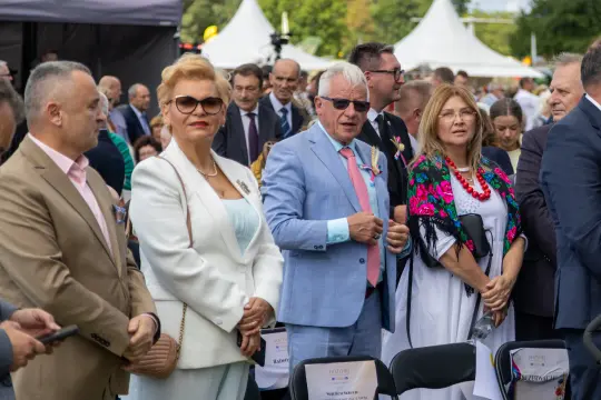 Grupa ludzi w eleganckich strojach na wydarzeniu plenerowym.