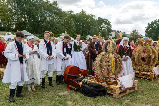 Uczestnicy tradycyjnego festiwalu w strojach ludowych, obok ozdobnych wieńców.