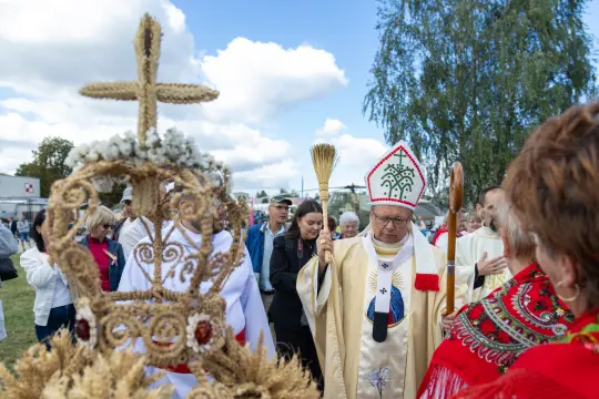 Uroczystość religijna z biskupem w tradycyjnym stroju, otoczonym przez wiernych.