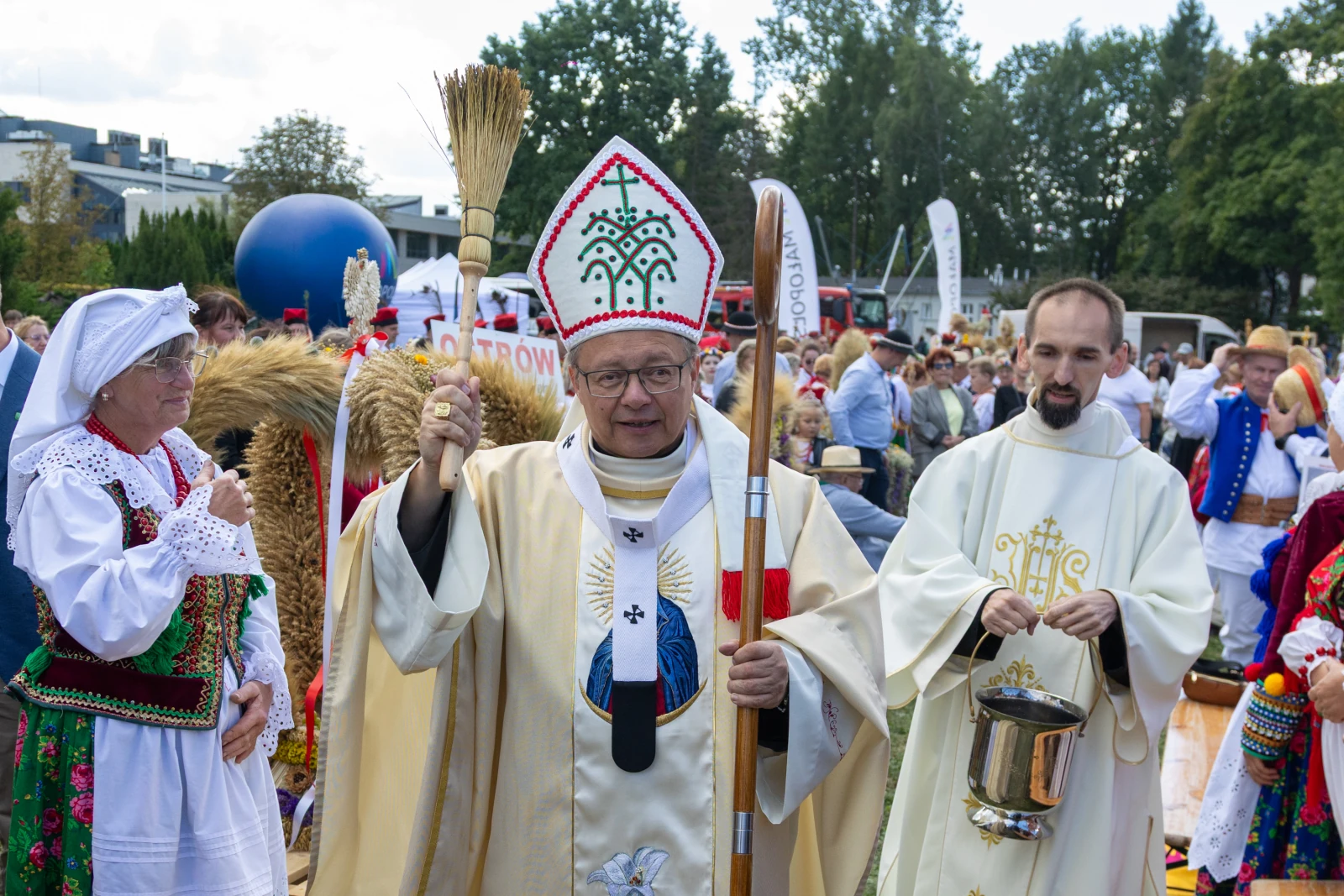 Ksiądz w szatach liturgicznych z pastorałem, obok osoby w tradycyjnym stroju ludowym.  Autor: Bogusław Świerzowski