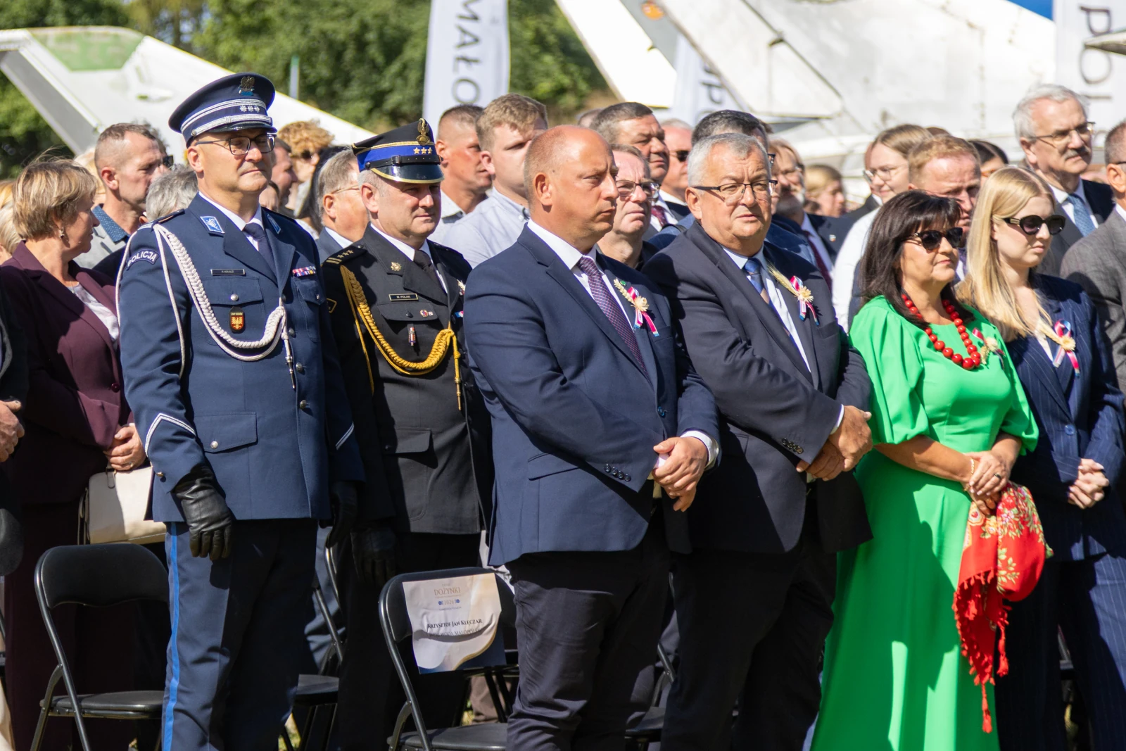 Uczestnicy uroczystości stoją w grupie, w różnych strojach, z poważnymi wyrazami twarzy.  Autor: Bogusław Świerzowski