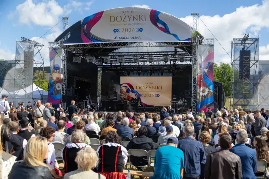 Tłum ludzi zgromadzonych na festiwalu dożynkowym z sceną w tle.