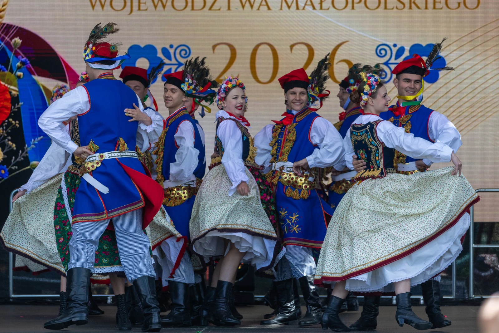 Grupa tancerzy w tradycyjnych strojach ludowych tańczy na scenie.  Autor: Bogusław Świerzowski