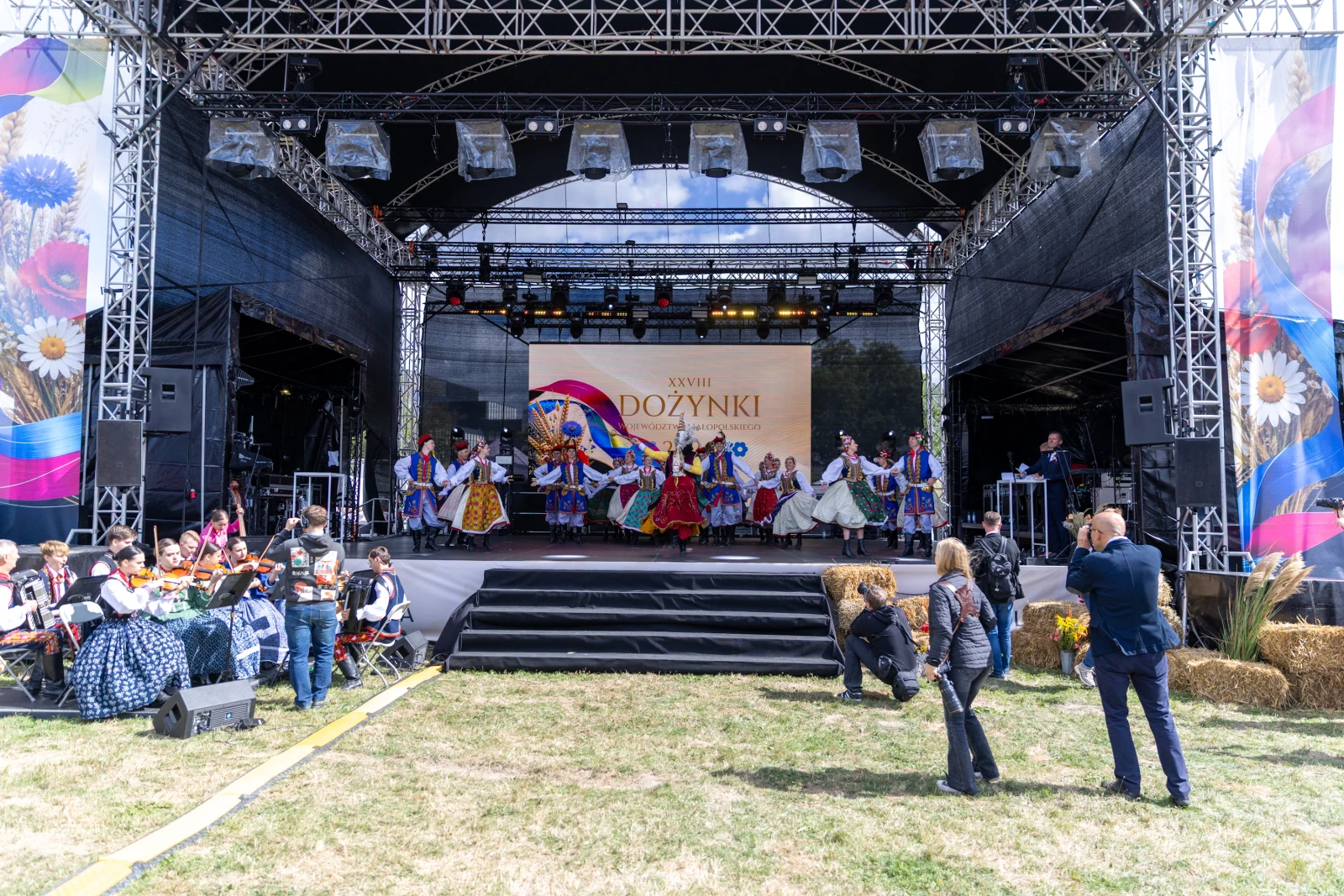 Uczestnicy dożynek tańczą na scenie, w tle dekoracje i publiczność.  Autor: Bogusław Świerzowski