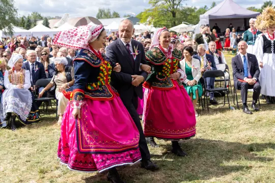 Mężczyzna w towarzystwie dwóch kobiet w tradycyjnych strojach ludowych tańczy na festiwalu.