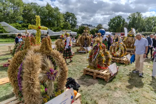 Wieniec dożynkowy ozdobiony kwiatami i zbożem, wystawiony na festiwalu.