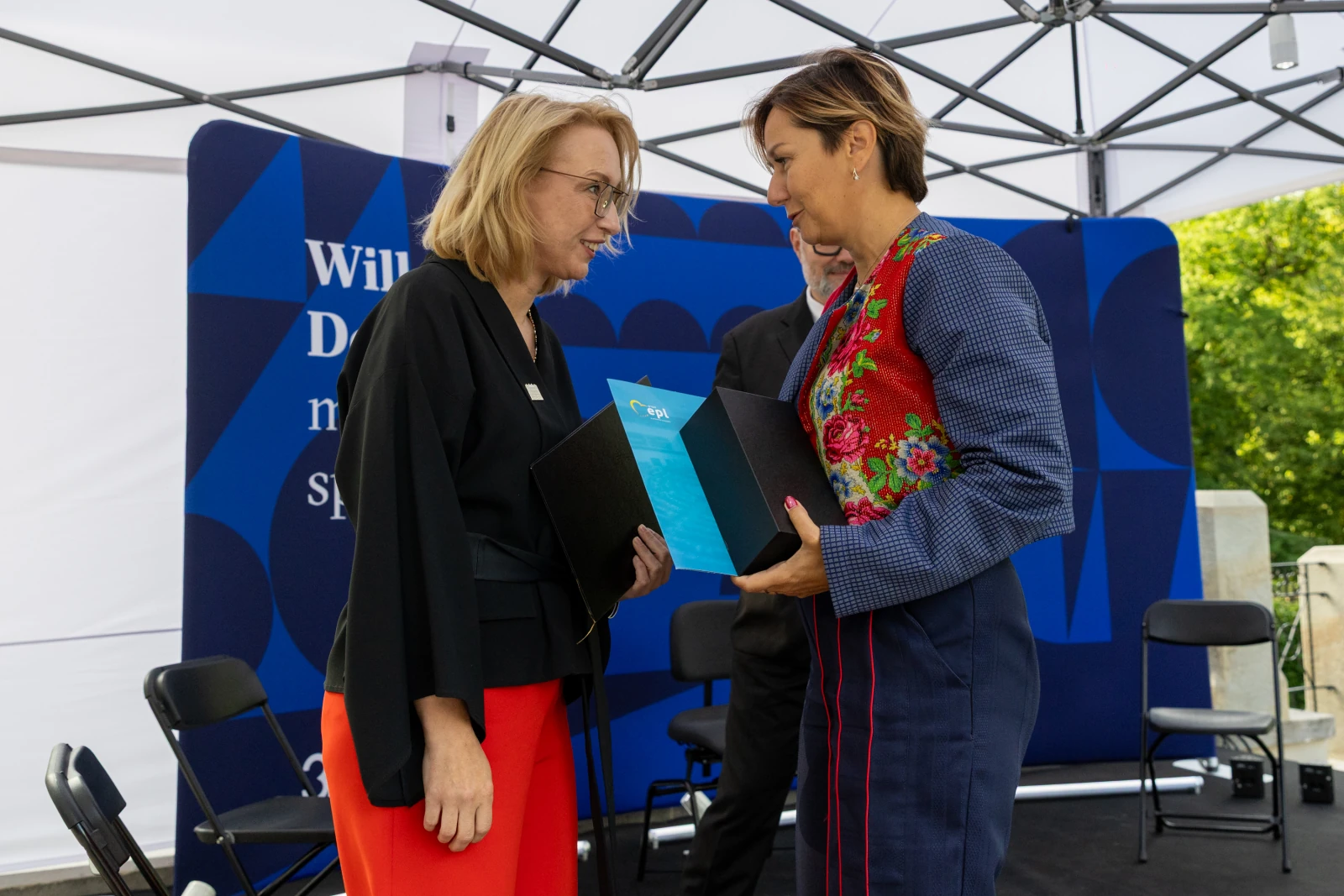 Dwie kobiety wymieniają się dokumentami podczas ceremonii.  Autor: Bogusław Świerzowski