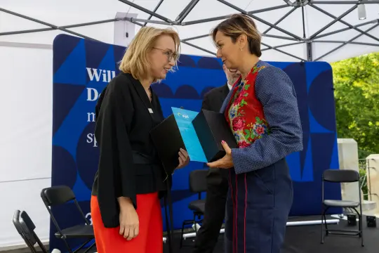 Dwie kobiety wymieniają się dokumentami podczas ceremonii.