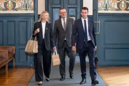 Trzech mężczyzn i kobieta w eleganckich strojach w stylowym wnętrzu.