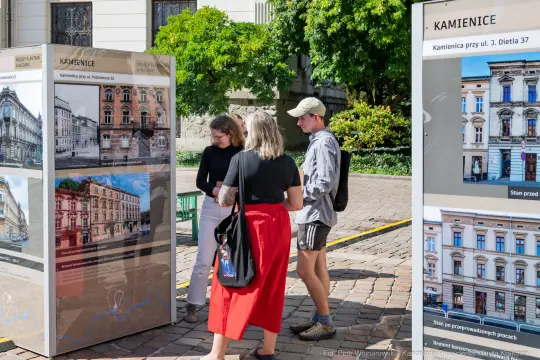 Trzy osoby oglądają wystawę o kamienicach przy ul. Ditelta 37.