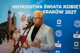 Mężczyzna przemawia na tle plakatu Mistrzostw Świata Kobiet w Krakowie 2027.