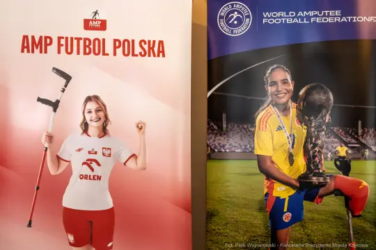 Kobieta z protezą nogi w koszulce AMP Futbol Polska obok innej zawodniczki z pucharem.