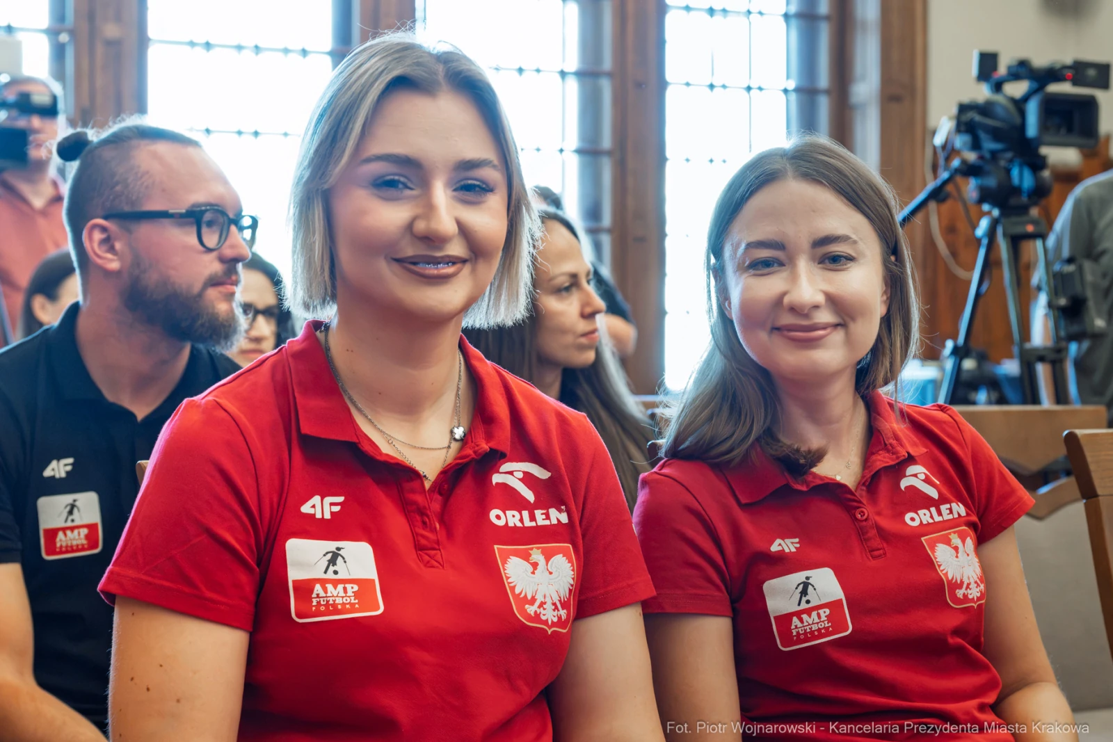 Dwie kobiety w czerwonych koszulkach z logo Orlen, uśmiechnięte, siedzące w sali.  Autor: Piotr Wojnarowski