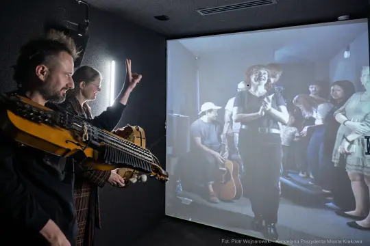Muzycy grający na instrumentach w interaktywnej przestrzeni z projekcją.