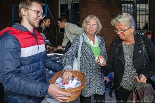 Mężczyzna wręcza kobietom losy z koszyka podczas wydarzenia.