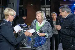 Grupa osób rozmawia i wymienia się kartkami w miejskim otoczeniu.