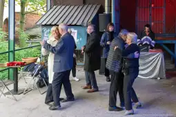 Ludzie tańczą w towarzystwie, w tle muzyka i oświetlenie.