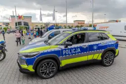 Policyjny samochód zaparkowany na parkingu, z niebieskimi i żółtymi oznaczeniami.