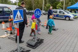 Dzieci uczą się zasad ruchu drogowego przy znakach i sprzęcie edukacyjnym.