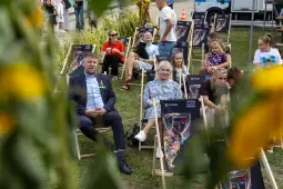 Grupa ludzi siedzących na leżakach podczas wydarzenia plenerowego.