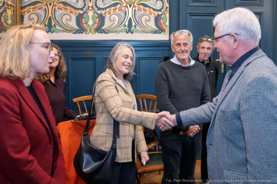 Spotkanie grupy ludzi, uściski dłoni i rozmowy w eleganckim wnętrzu.