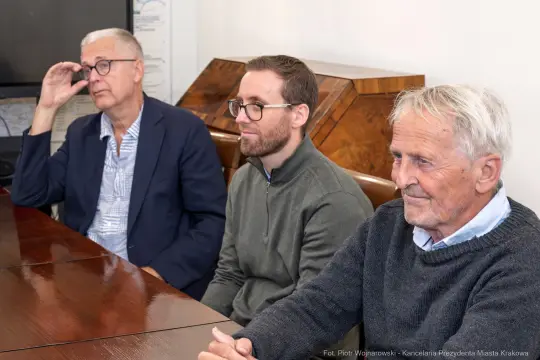 Trzech mężczyzn siedzących przy stole w biurze.