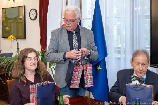 Spotkanie z wręczeniem upominków, w tle flagi Polski i Unii Europejskiej.