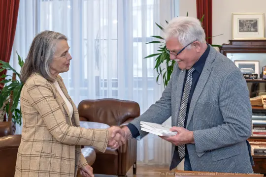 Spotkanie dwóch osób, uścisk dłoni, wymiana dokumentów w biurze.